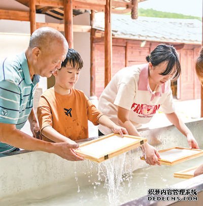 游客在福建泉州一家古法造纸技艺馆体验捞纸。许华森摄（影像中国）